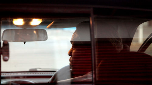 Rear view of man traveling in car seen through rear windshield