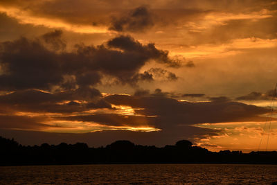 Scenic view of dramatic sky over silhouette trees during sunset