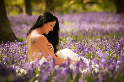 Woman sitting amidst purple flowers on field