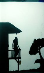 Silhouette man by railing against sky