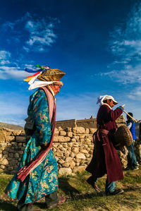 Woman in traditional clothing at beach against blue sky