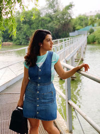 Young woman looking away while standing by railing