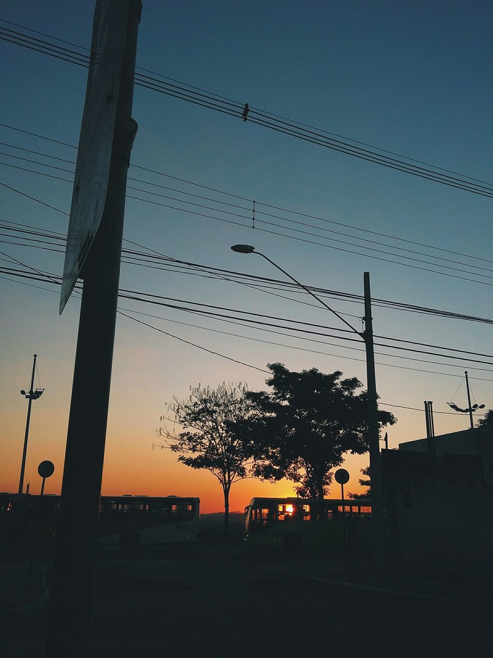 silhouette, power line, sunset, electricity pylon, cable, electricity, connection, power supply, sky, low angle view, fuel and power generation, built structure, clear sky, building exterior, architecture, dusk, technology, power cable, tree, street light