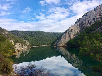 Scenic view of lake by mountains against sky