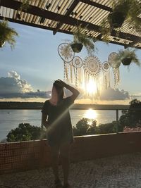 Rear view of woman standing by plants against sky