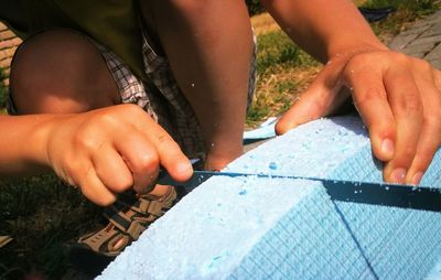 Low section of boy cutting polystyrene