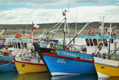 Boats moored at harbor in sea against sky