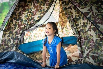 Cute girl looking away while kneeling in tent