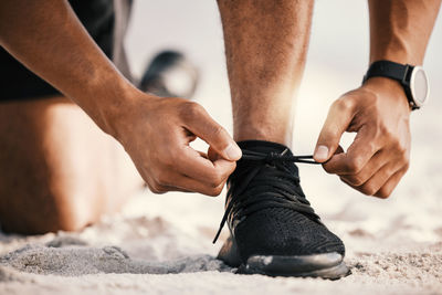 Low section of man tying shoelace