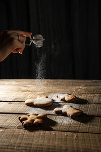 Midsection of person holding cookies on table