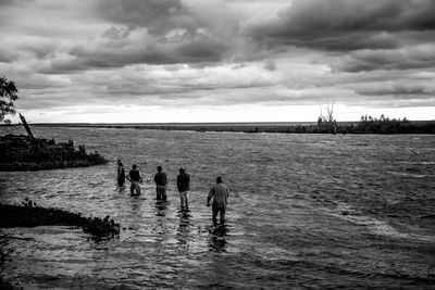 People standing in sea against sky