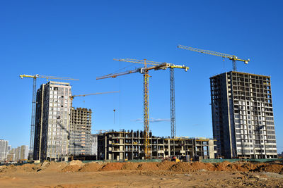 Tower cranes working at construction site on blue sky background. 