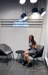 Full length of woman sitting on chair against wall