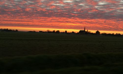 Scenic view of silhouette field against orange sky