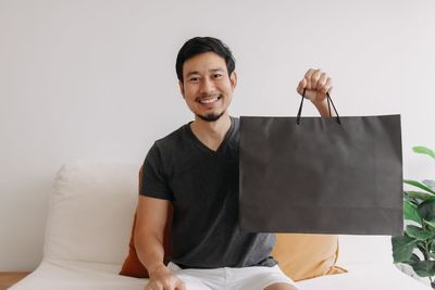 Portrait of young woman using digital tablet while sitting on bed at home
