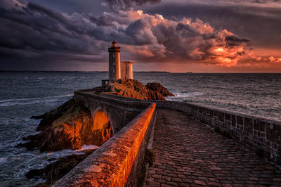 Scenic view of sea against dramatic sky at sunset