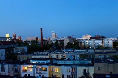 Illuminated cityscape against clear blue sky