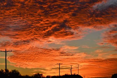 Low angle view of electricity pylon against dramatic sky