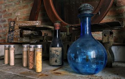 Close-up of old bottles on table against wall