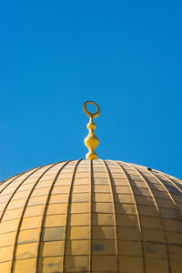 Low angle view of cross against building against clear blue sky