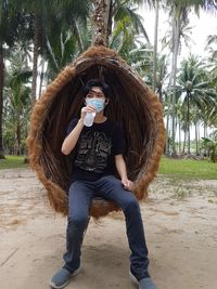 Full length of young woman holding palm tree