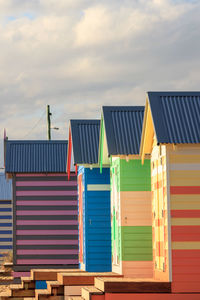 Low angle view of multi colored beach huts against sky