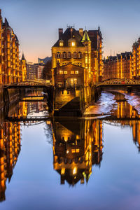 Reflection of illuminated bridge over river in city at night