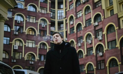 Full length of young woman standing against building