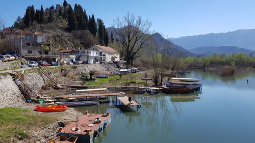 Boats moored on river by buildings against sky