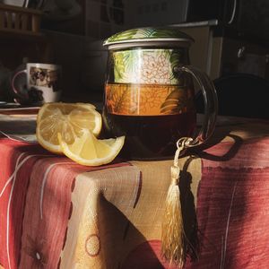 Close-up of half lemon by teapot on table