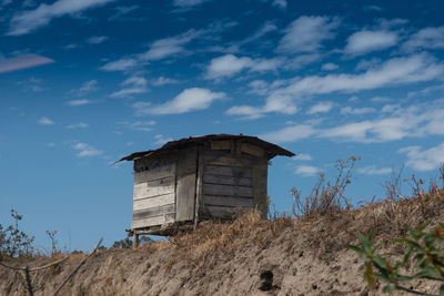 Low angle view of wooden hut on field against blue sky