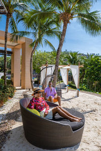 People sitting by palm tree