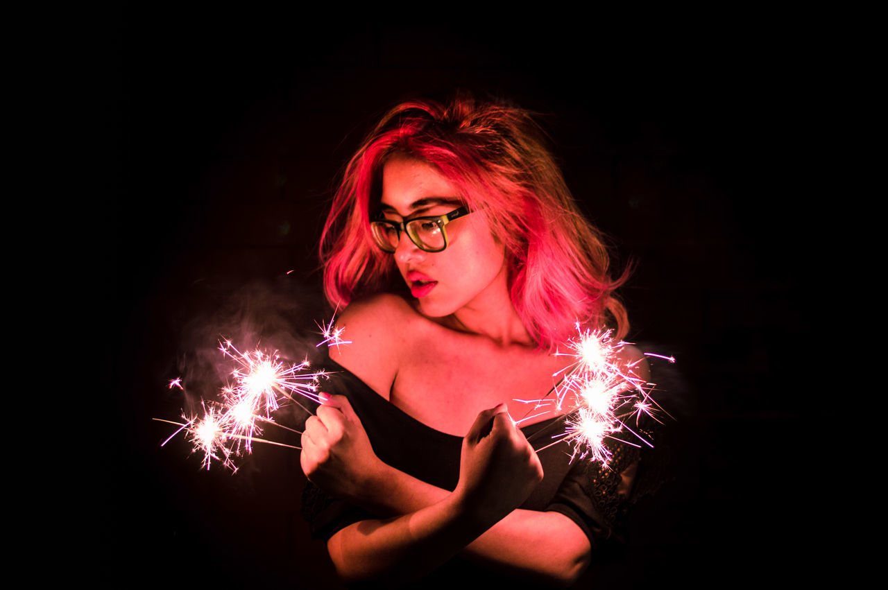 sparks, glowing, redhead, one person, sparkler, burning, firework - man made object, illuminated, young adult, holding, young women, long exposure, black background, night, heat - temperature, flame, red, dyed hair, adult, real people, portrait, beautiful woman, one young woman only, indoors, one woman only, adults only, witch, halloween, people