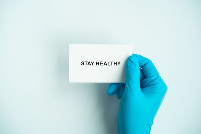 Close-up of hand holding paper against white background