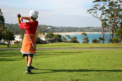 Rear view of man playing soccer on golf course