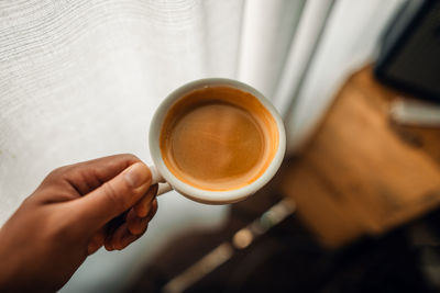 Midsection of woman holding coffee on table