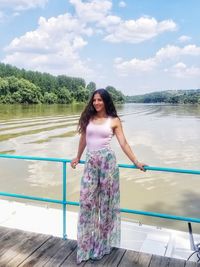 Woman standing by railing against lake