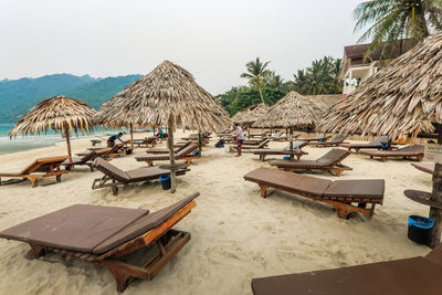 Lounge chairs and tables on beach against clear sky