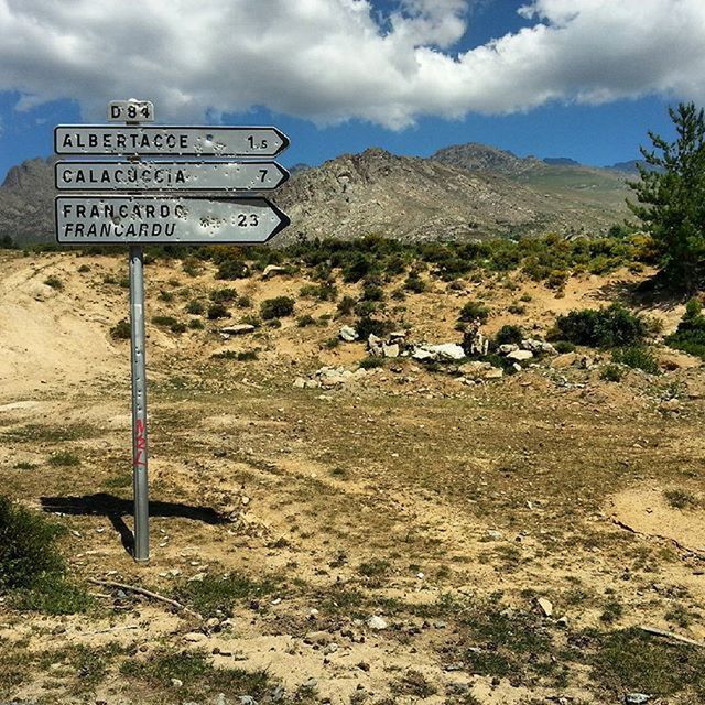 text, western script, sky, communication, mountain, cloud - sky, information sign, sign, landscape, road sign, tranquil scene, tranquility, guidance, cloud, warning sign, tree, nature, scenics, arrow symbol, non-western script