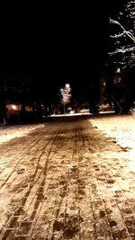 Illuminated street amidst buildings during winter at night