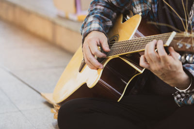 Midsection of man playing guitar