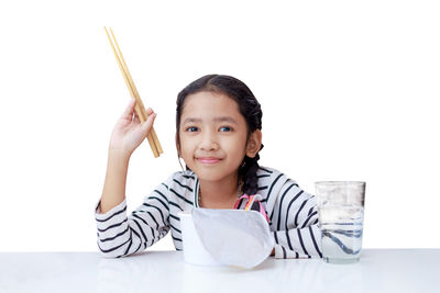 Portrait of smiling girl holding ice cream against white background