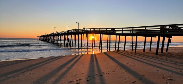 Pier over sea against clear sky during sunset