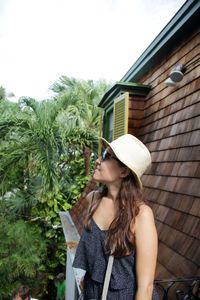 Young woman wearing hat while standing against plants