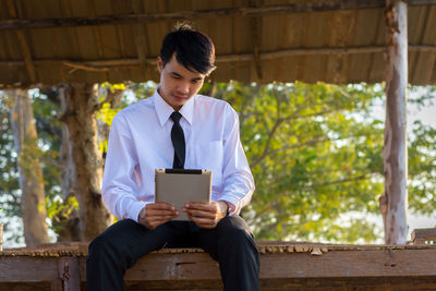 Low angle view of businessman using digital tablet while sitting outdoors
