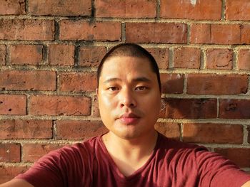 Close-up portrait of man against brick wall