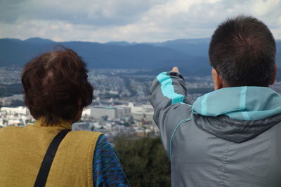 Rear view of man and woman looking at mountains against sky