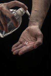 Close-up of person holding hands against black background