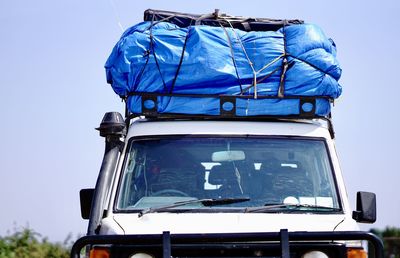 Low angle view of tents on 4 wheel drive vehicle against blue sky