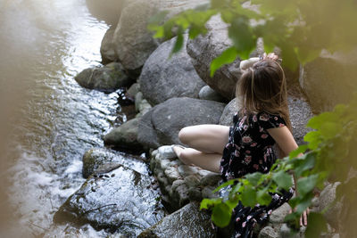 Rear view of woman sitting on rock